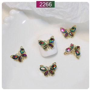 Macro detail of 3D gold alloy butterfly nail charms with iridescent crystal rhinestones