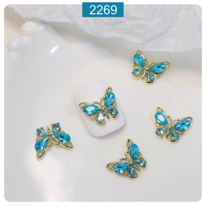 Detailed macro view of 3D gold alloy butterfly nail charms with blue crystals