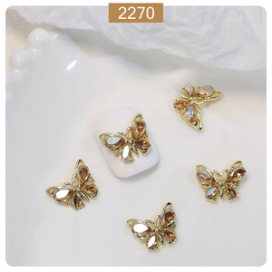 Detailed macro view of 3D gold butterfly nail art charms with amber zircons and crystals
