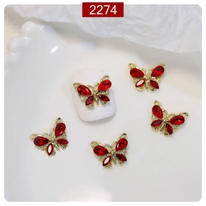 Macro shot of 3D red crystal butterfly nail charms with golden alloy base on a white nail