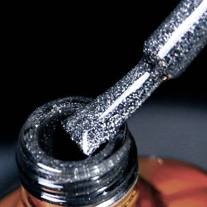 Macro shot of black cat-eye nail polish brush with sparkling silver glitter particles