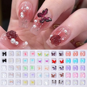 Macro detail of 3D aurora butterfly and resin flower nail art charms on fingertips