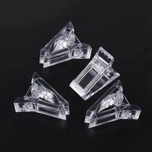 Detailed view of four transparent nail extension clips on a professional black background