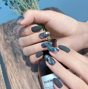 Dunkelgraue matte Nägel mit Sternenblau-Glitzer, 3D-Strasssteinen und schwarzen Perlen