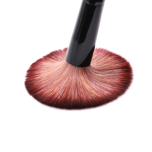 Macro shot of fan-shaped makeup brush with dense red-brown gradient bristles and black handle