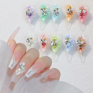 Macro detail of 3D floral nail charms with rhinestones and pearls on French manicure
