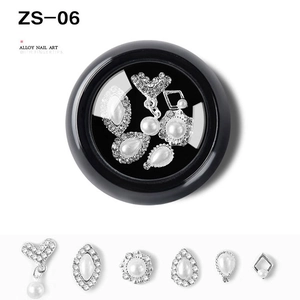 Detailed close-up of alloy nail art charms with pearls and rhinestones in a display box