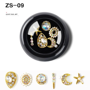 Macro detail of alloy nail charms set with rhinestones and pearls in a black round box