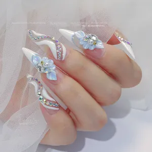 Macro detail of ice blue stiletto nails with 3D resin flowers, pearls and glitter accents