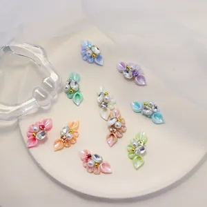 Macro shot of 3D resin flower nail charms with pearls and rhinestones in pastel colors