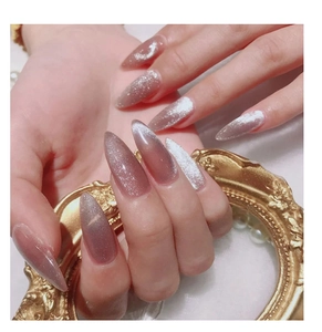 Cat eye nail art in dusty rose with glitter accents shown on long pointed almond nails