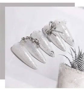Macro di unghie press-on glitterate con fiocchi argentati, perle e strass lucidi