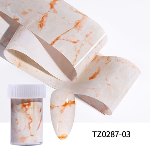 Detail of marble pattern nail transfer foil with orange-brown swirls and storage bottle