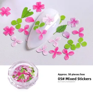 Detailweergave van kleurrijke 3D-bloem en blad nageldecoraties in een opbergdoosje
