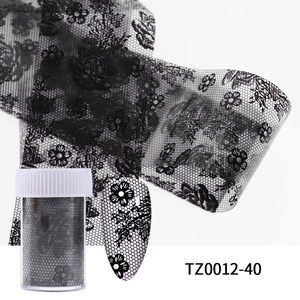 Close-up of black lace floral nail art foil with bottle and applied nail tip effect