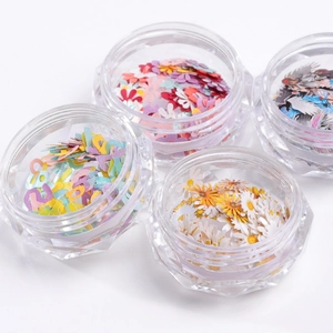 Kleurrijke nail art houtpulp schijfjes met bloemen en letters in vier potjes