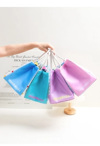 Detail of colorful fabric lunch bags with white cotton rope handles in various pastel tones