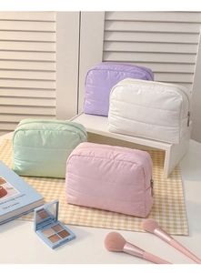 Close-up of four quilted down makeup bags in pastel colors with high-shine nylon finish