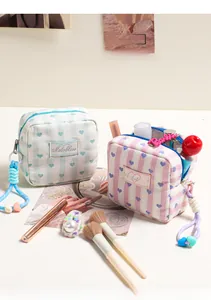 Close-up of fabric pouch with striped pattern, heart embroidery, and woven rope zipper