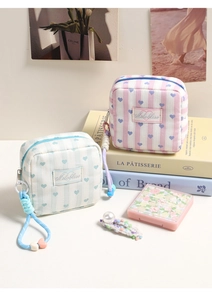 Detail of striped heart makeup pouches with side zipper and braided heart strap charms