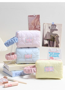Tre beauty case trapuntati a cuore in colori pastello con manici arricciati da donna