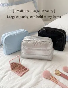 Close-up of three puffer quilted cosmetic bags in blue silver and black colors