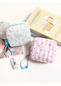 Detail of canvas pouches with vertical stripes and heart patterns featuring braided wristlets