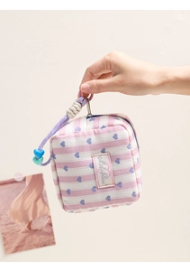 Close-up of pink striped mini cosmetic bag with blue heart pattern and heart charm
