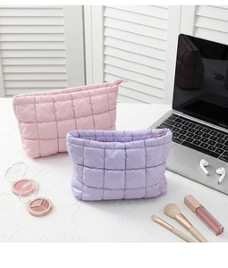 Detailweergave van gewatteerde nylon make-up tassen in roze en paars met rits