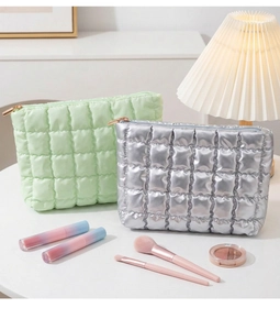 Close-up of quilted puffy makeup bags in light green and silver with metallic zippers