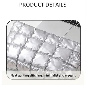 Detailopname van de zilveren gewatteerde textuur en metallic afwerking van de make-uptas