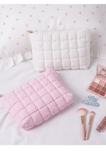 Close-up of quilted puff makeup bags in pink and white with metallic zippers