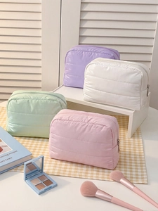 Quilted waterproof makeup bags in four pastel colors on a shelf with makeup brushes