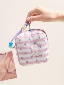 Striped canvas makeup bag with blue heart pattern and purple wrist strap in hand