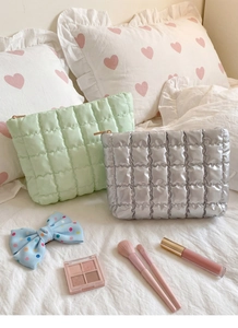 Close-up of quilted makeup bags in mint green and silver with gold zippers