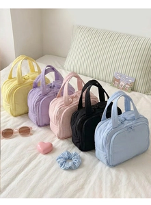 Various colors of quilted cotton makeup bags with top handles and zippers displayed