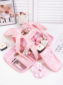 Detail of light pink travel makeup bag showing multiple brush slots and mesh pockets