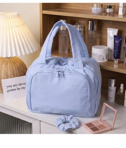 Detail of light blue quilted cotton makeup bag with dual zippers and carry handle