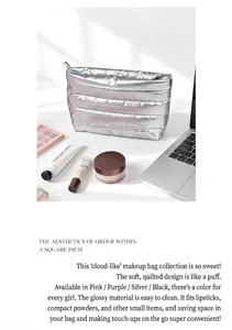 Detailed close-up of a silver quilted cloud-style pouch with cosmetics on a white desk