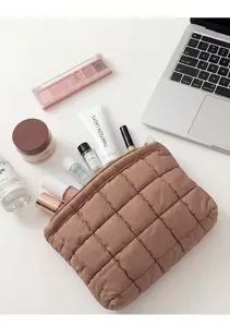 Neceser acolchado marrón en escritorio con portátil y productos de cuidado facial