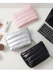 Flat lay of three quilted makeup bags in pink, silver, and black with silver zippers