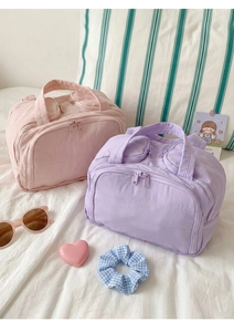Close-up of quilted cotton cosmetic bags in pink and purple with dual zippers and handles