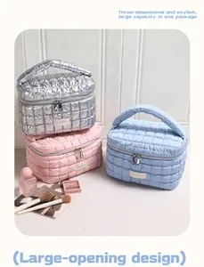 Drei gesteppte Make-up-Taschen in Silber, Rosa und Blau auf Holzuntergrund gestapelt