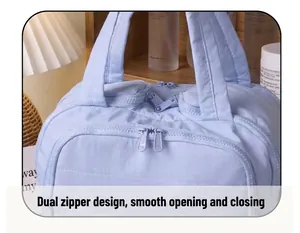 Macro detail of dual-zipper closure on light blue quilted cotton travel cosmetic bag