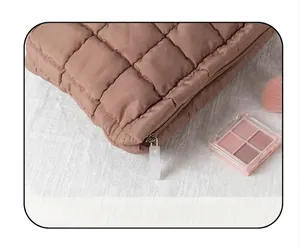 Primer plano de bolsa de maquillaje acolchada con cremallera suave y textura de rombos