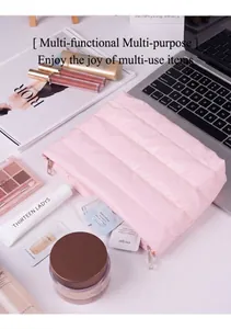 Pink quilted cosmetic bag with metal zippers displayed on a desk with lifestyle accessories