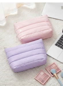 Close-up of quilted cosmetic bags in pink and purple on white plush rug