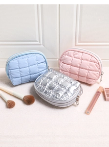 Close-up of three quilted shell cosmetic bags in blue, pink, and silver with metal zippers
