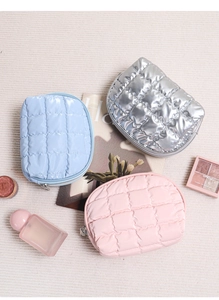 Close-up of three quilted cosmetic bags in silver, blue, and pink glossy finish