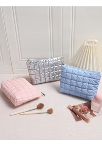 Close-up of quilted makeup bags in silver, blue and pink with a soft glossy texture